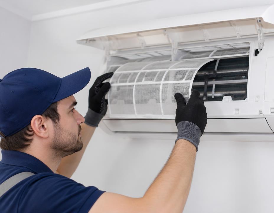 Technicien réalisant l'entretien d'un climatiseur mural